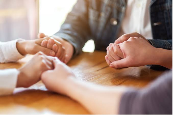 Two people offering comfort by holding hands